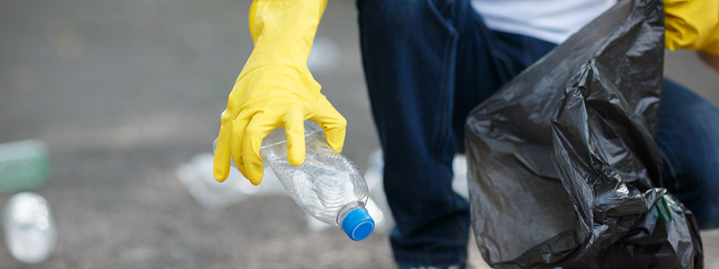 Person with a black bin bag wearing yellow rubber gloves