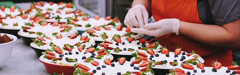 Hands with gloves preparing food for an event