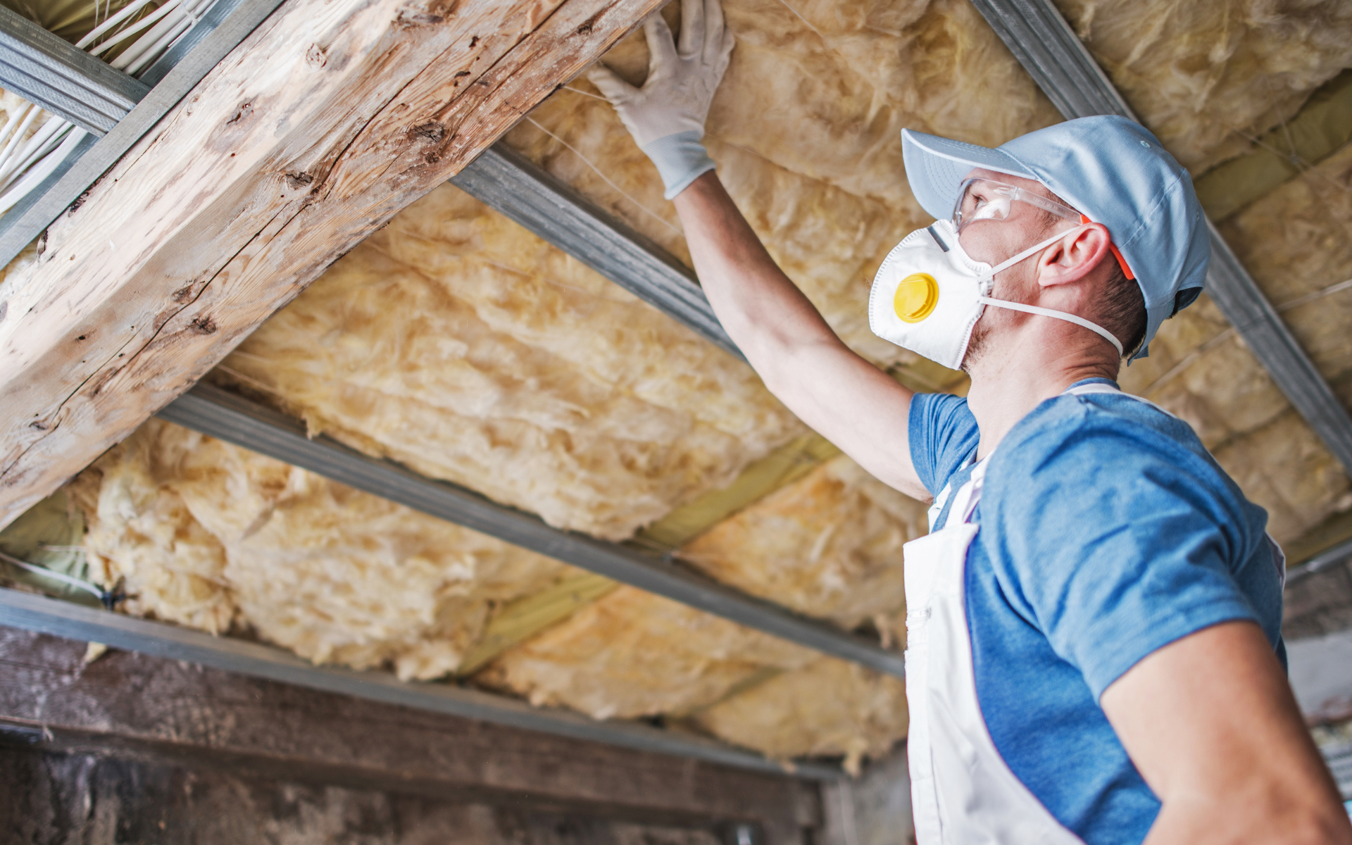 A labourer installing lagging into an attic