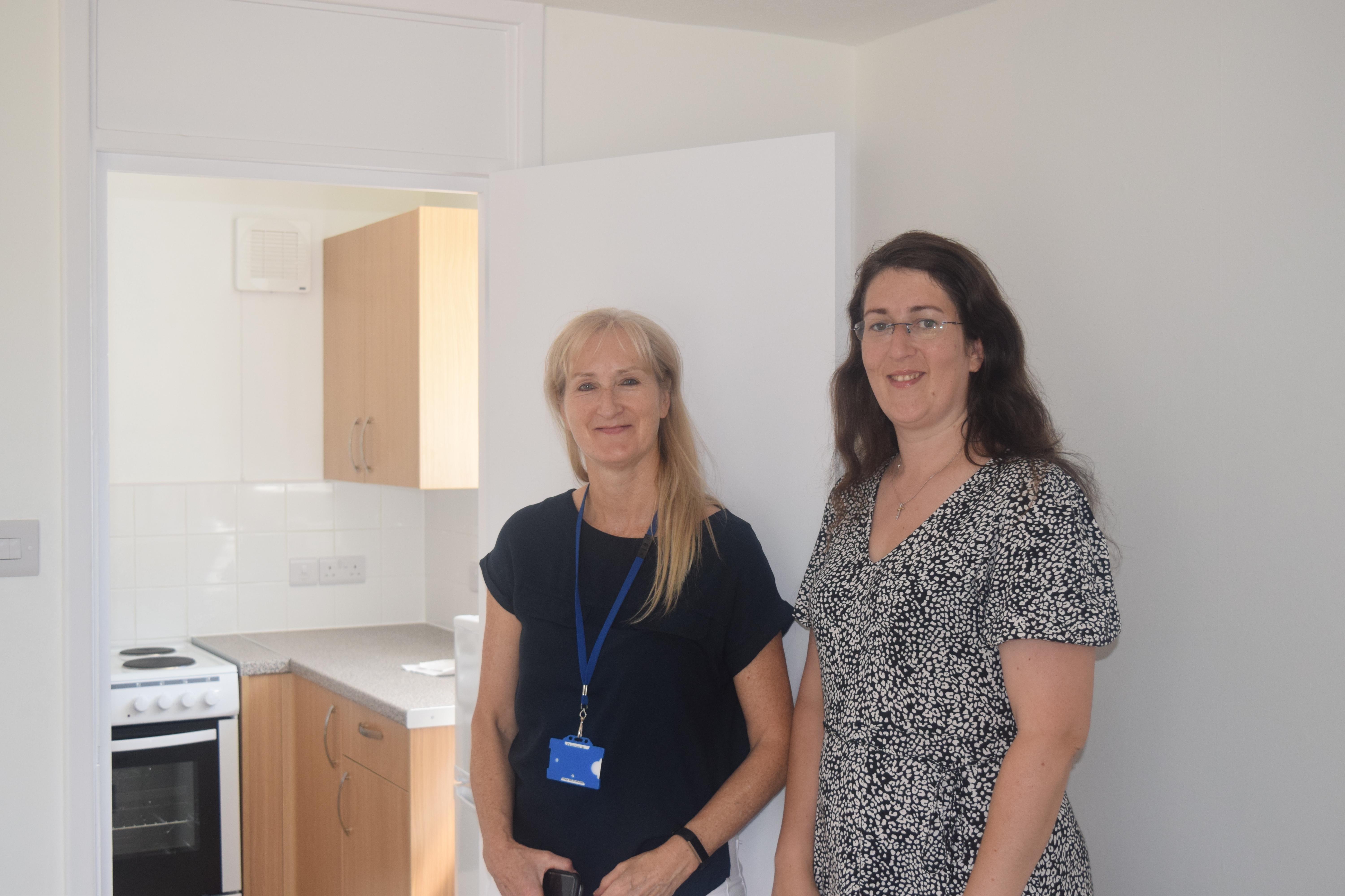 Maggie Ward and Cllr Jacqui Gracey next to an open door leading to a kitchen