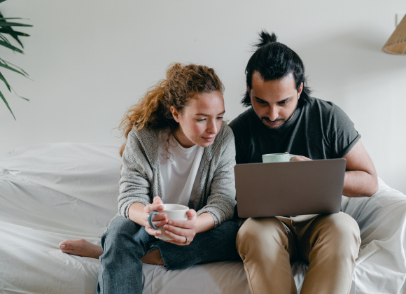 Couple on their sofa looking at laptop.