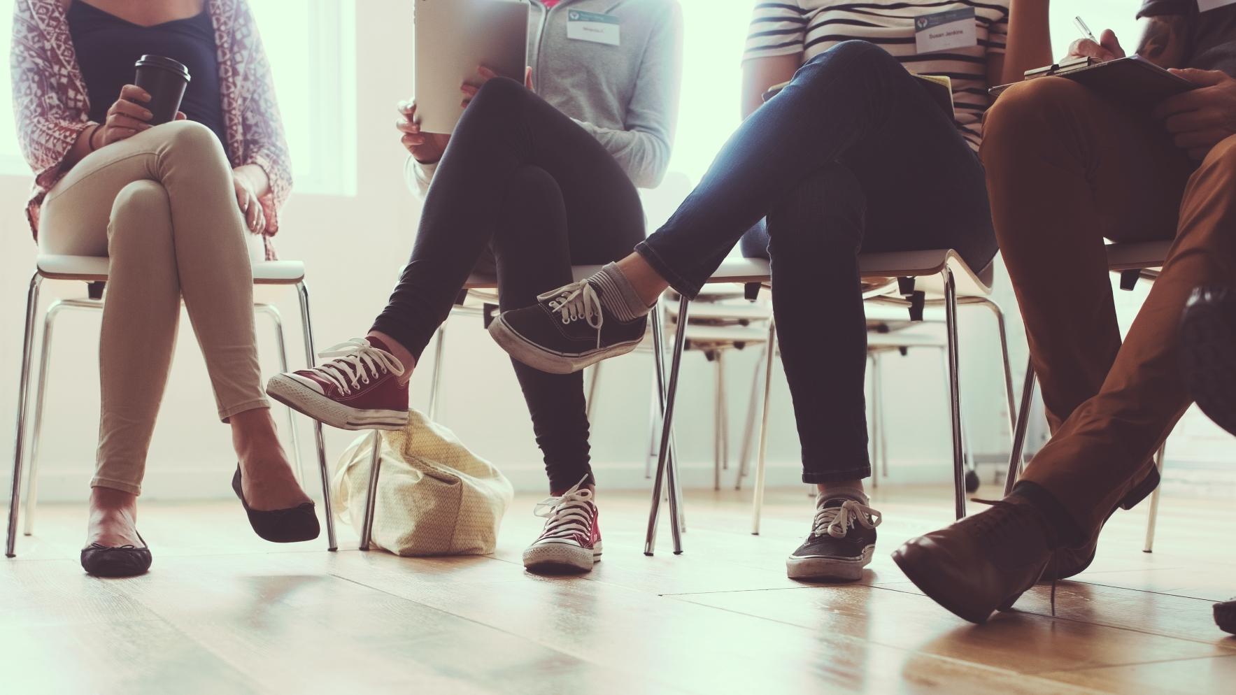 Group of four young people sitting in chairs talking